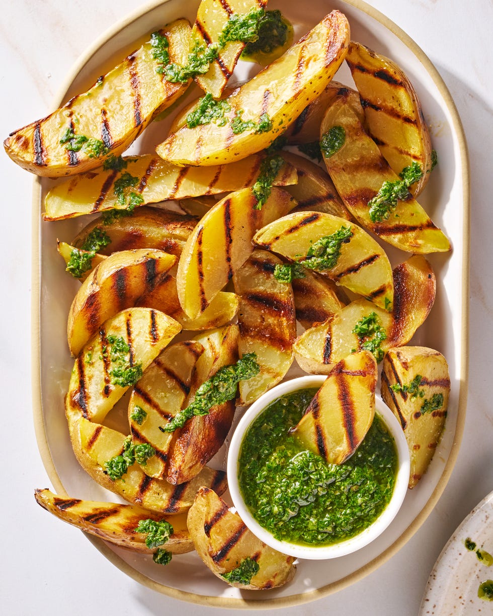 grilled potatoes on a platter topped with herby green sauce