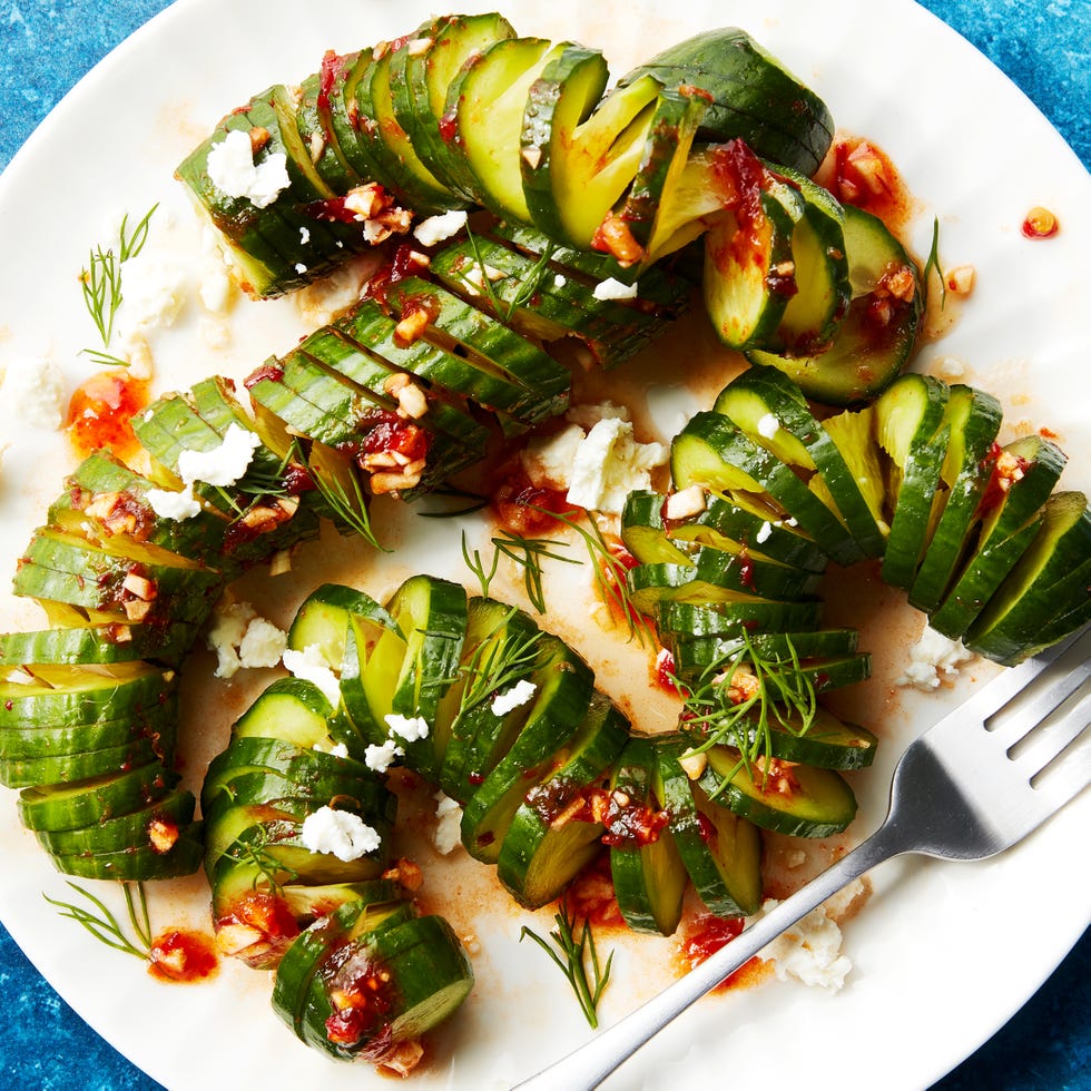 viral spiral cucumber salad topped with harissa dressing and feta on a white plate