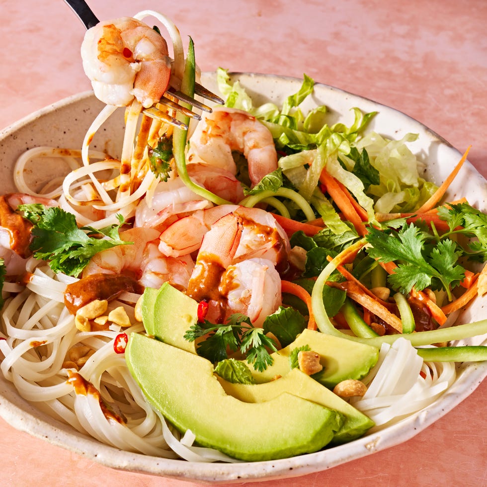 fork lifting a bite of summer roll bowl with rice noodles, shrimp, avocado, and peanuts