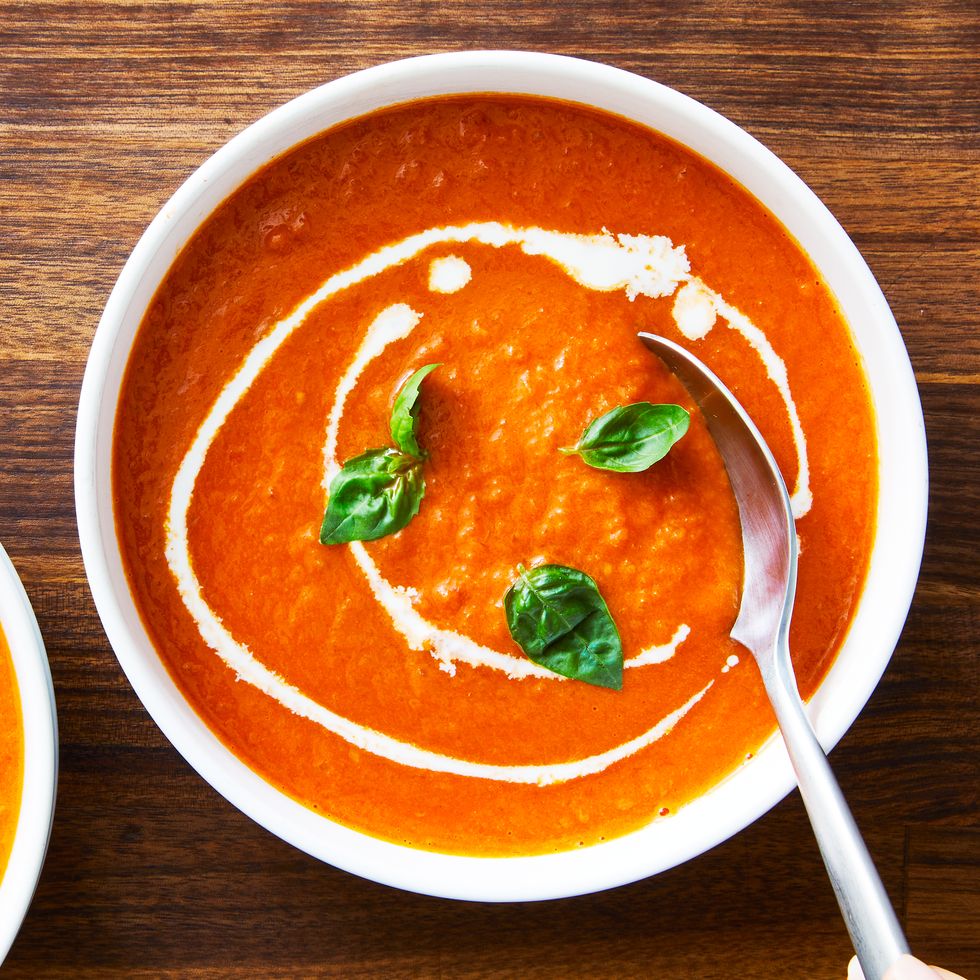 bowl of tomato soup topped with basil and swirls of heavy cream
