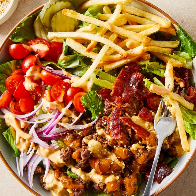 a bed of fresh romaine lettuce topped with everything you'd find on a classic american diner cheeseburger, tangy dill pickles, thinly sliced red onion, juicy tomatoes, smoky bacon, cheddar cheesy ground beef, a drizzle of burger sauce, and of course a few golden crispy fries