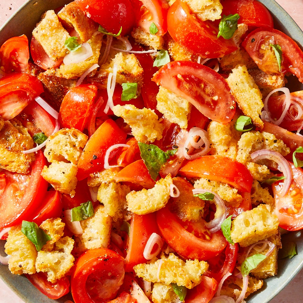 a bowl of panzanella salad with basil and shallots