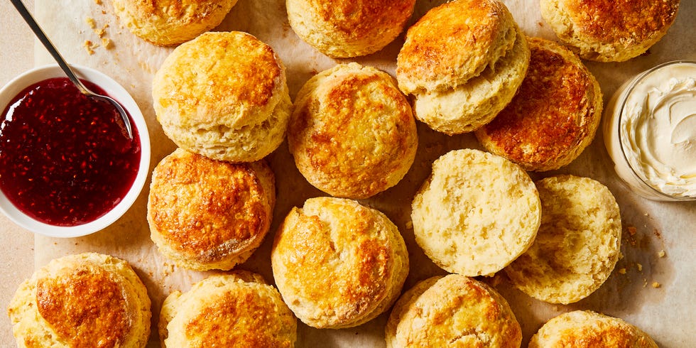 scones on parchment paper with bowls of jam and clotted cream