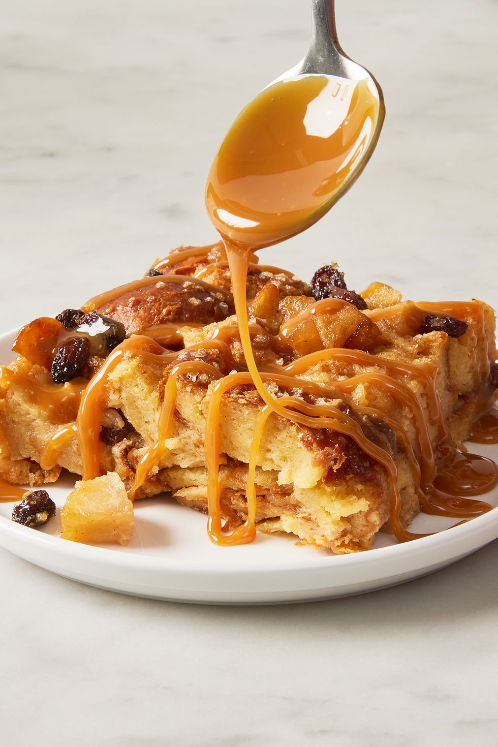 apple bread pudding on a plate drizzled with caramel sauce