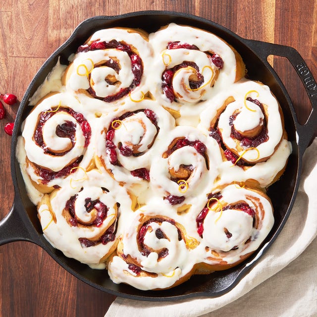 fluffy cinnamon rolls with brown sugar and cranberry filling baked in heavy cream and topped with orange glaze