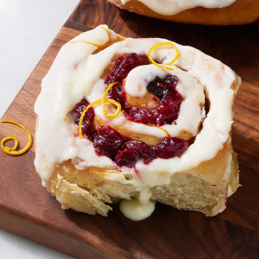 fluffy cinnamon rolls with brown sugar and cranberry filling baked in heavy cream and topped with orange glaze