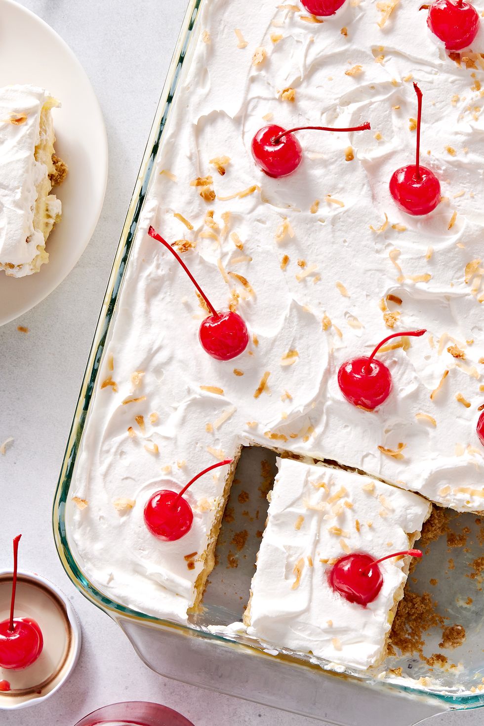 creamy coconut lime cheesecake layered with buttery shortbread cookies, crushed pineapple jello, cool whipped cream, and maraschino cherries all on a graham cracker coconut crust