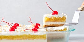 creamy coconut lime cheesecake layered with buttery shortbread cookies, crushed pineapple jello, cool whipped cream, and maraschino cherries all on a graham cracker coconut crust