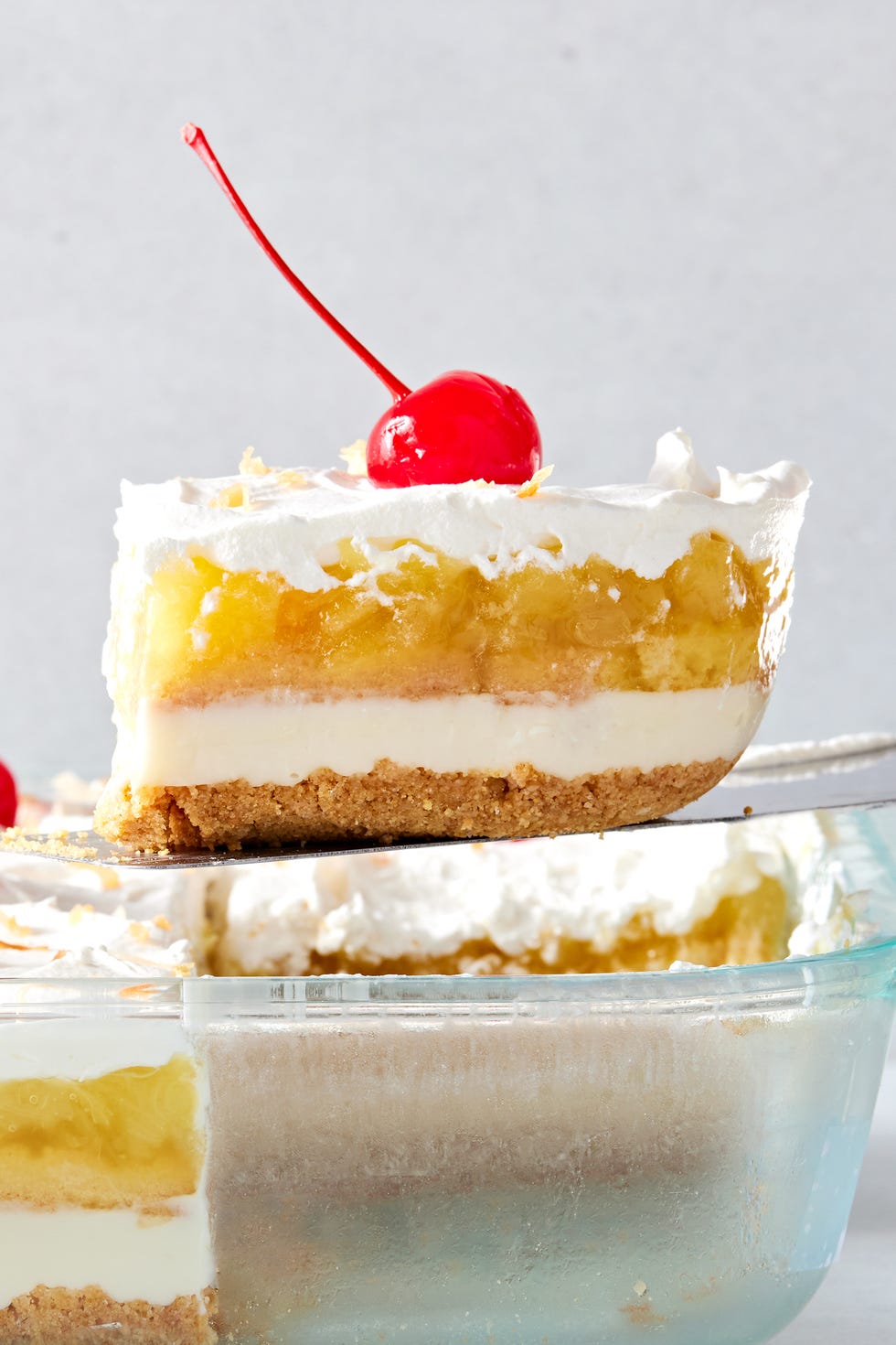 creamy coconut lime cheesecake layered with buttery shortbread cookies, crushed pineapple jello, cool whipped cream, and maraschino cherries all on a graham cracker coconut crust