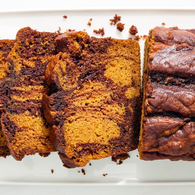 a loaf of pumpkin bread with a nutella swirl throughout the batter beside three slices