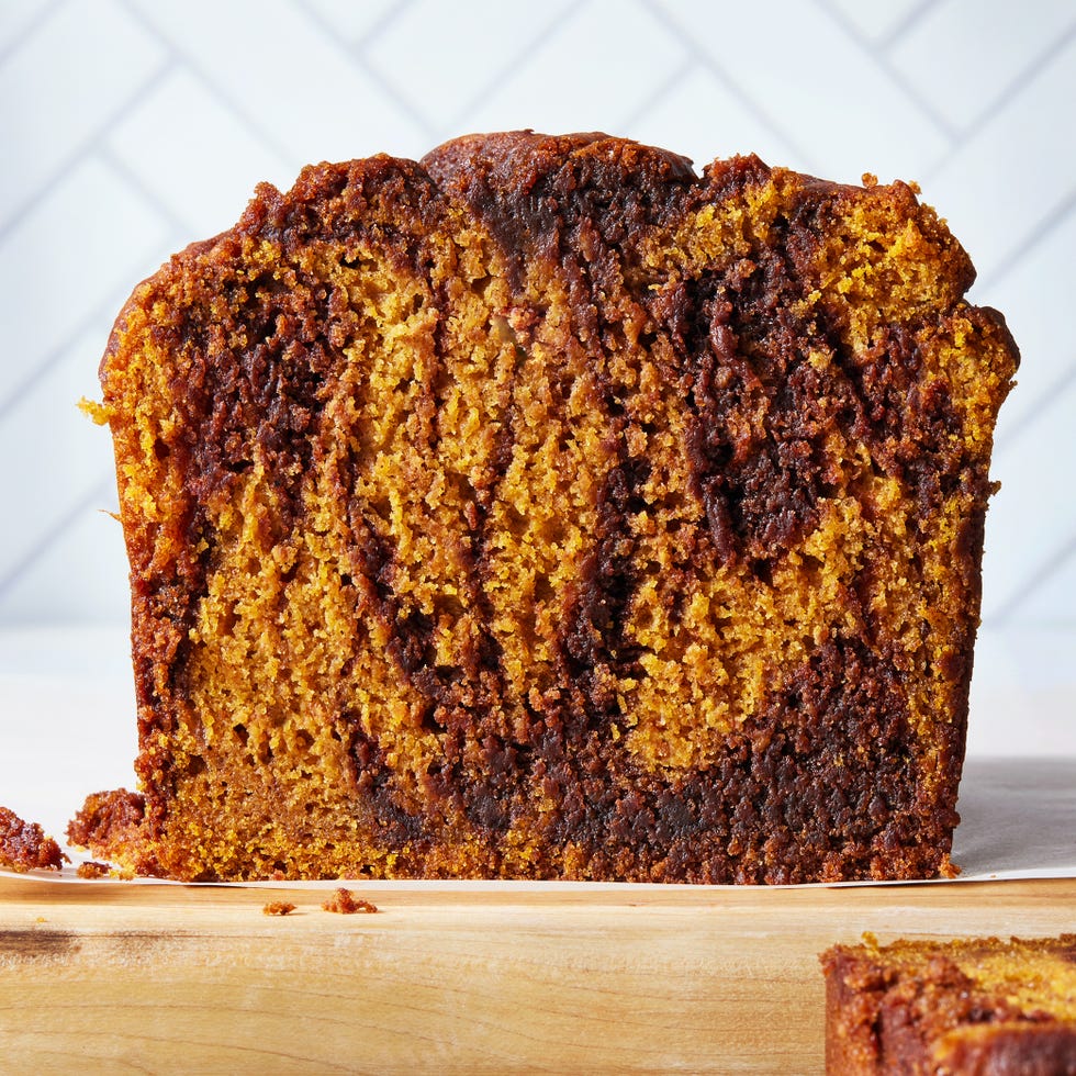 a loaf of pumpkin bread with a nutella swirl throughout the batter beside three slices