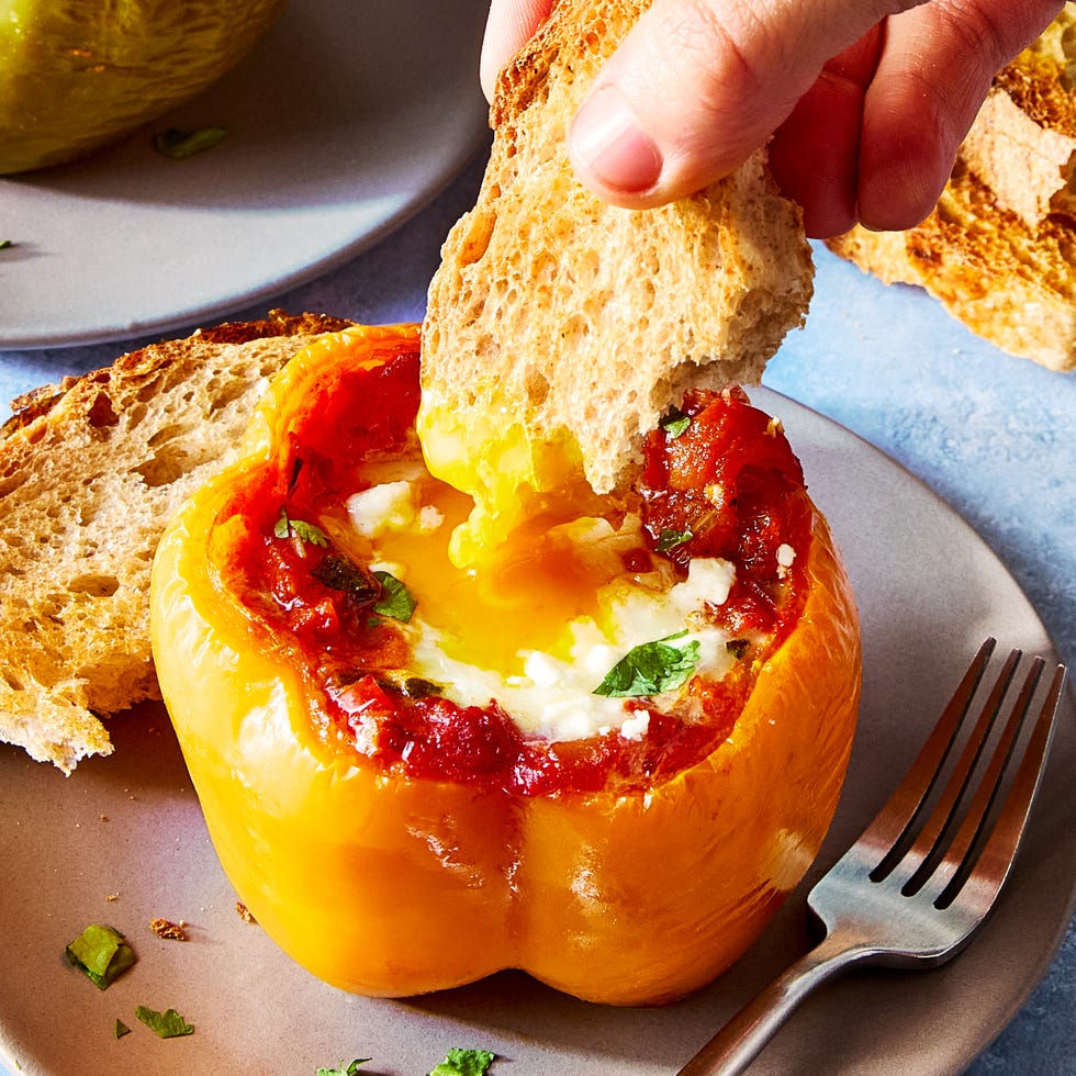 shakshuka stuffed pepper on a white plate with a piece of toast being dunked in