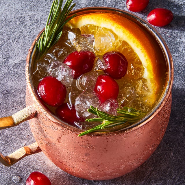 Yule Mule cranberry orange mule served in copper mugs and garnished with fresh cranberries, orange slices, and rosemary sprigs