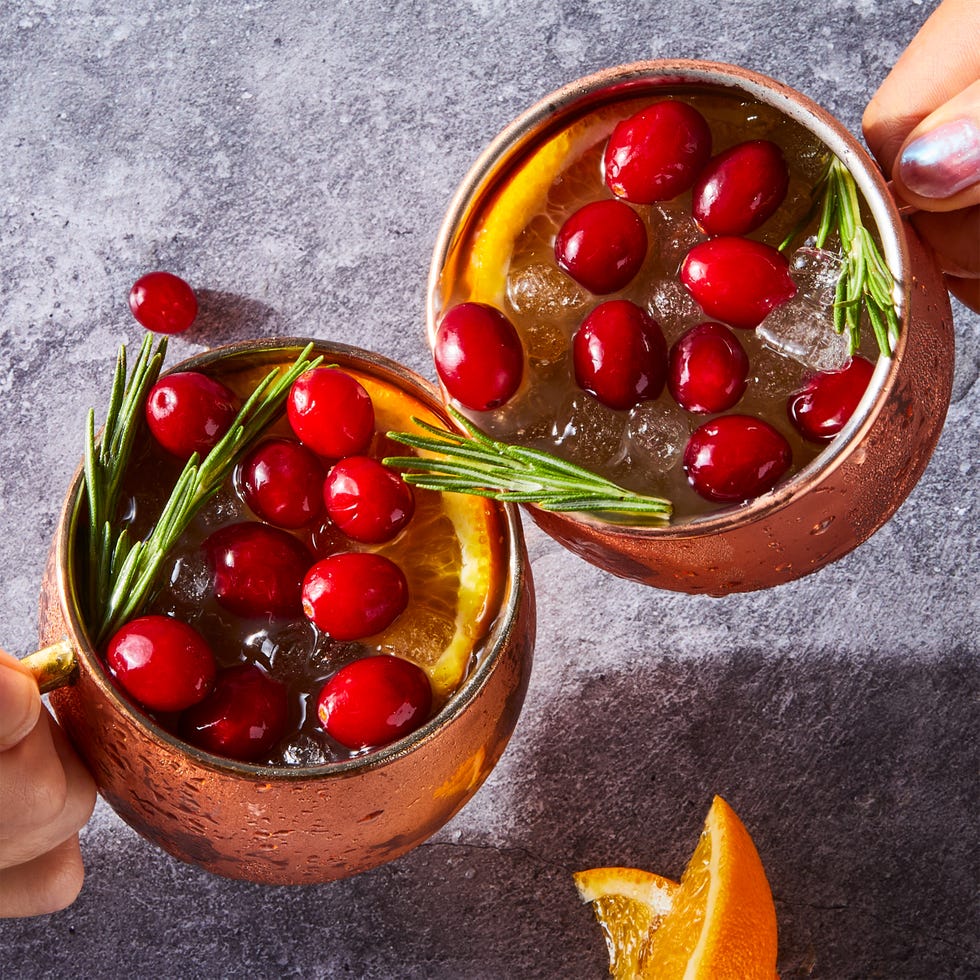 cranberry orange mule served in copper mugs and garnished with fresh cranberries, orange slices, and rosemary sprigs