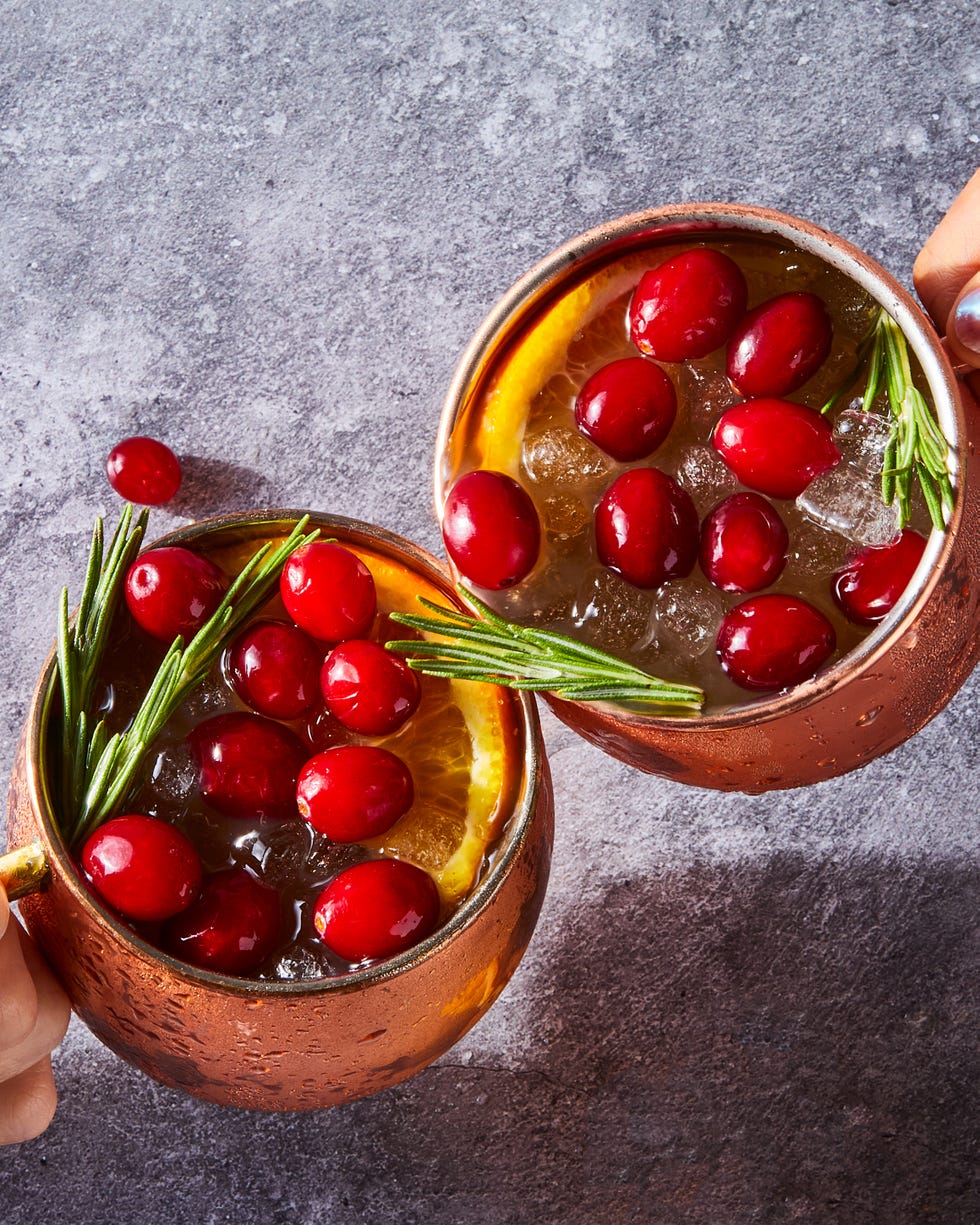 cranberry orange mule served in copper mugs and garnished with fresh cranberries, orange slices, and rosemary sprigs