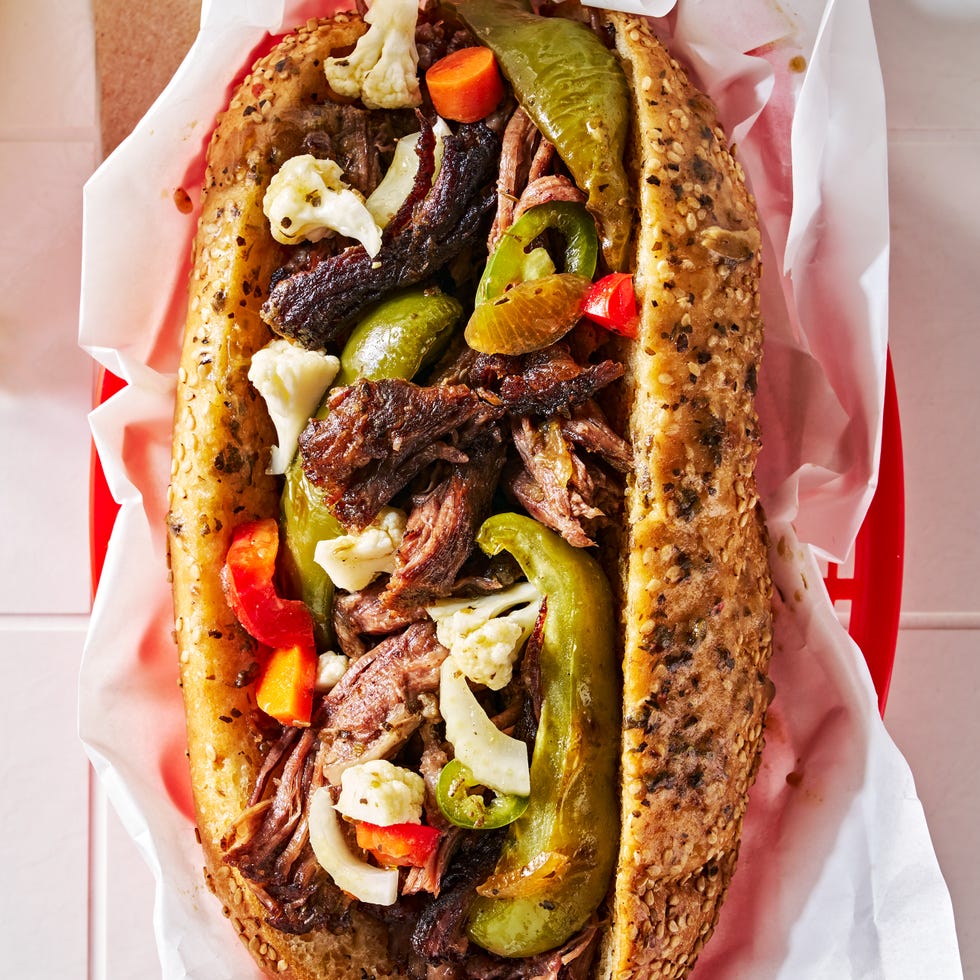 a classic chicago sandwich with slow roasted seasoned beef piled on a soft sub roll with giardiniera and roasted green peppers