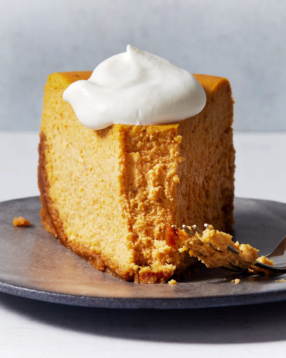 pumpkin cheesecake on plate topped with whipped cream with a fork