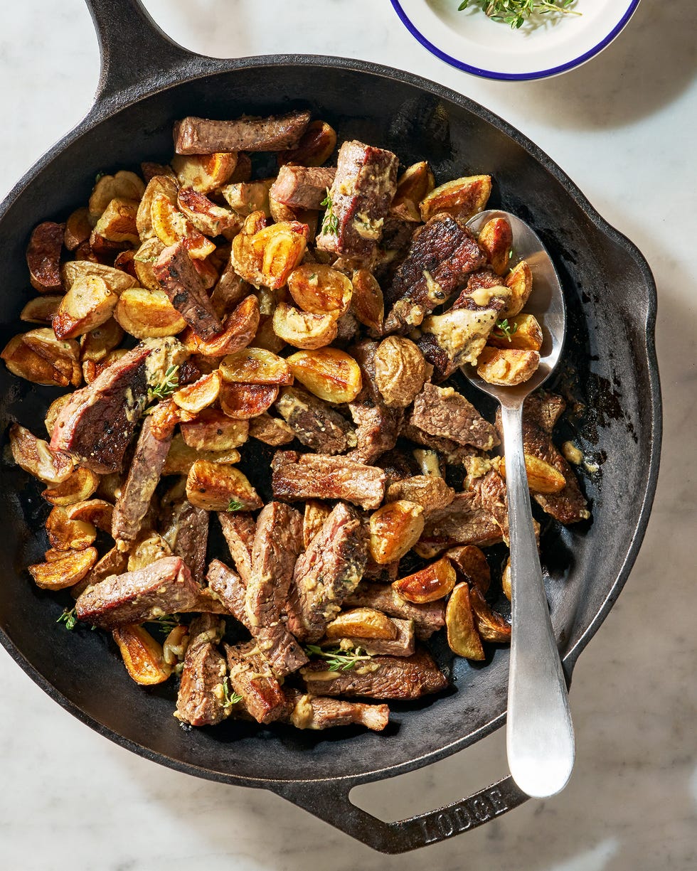 a skillet of crispy potatoes and tender, seared flank steak bathed in a tangy, savory garlic mustard butter sauce