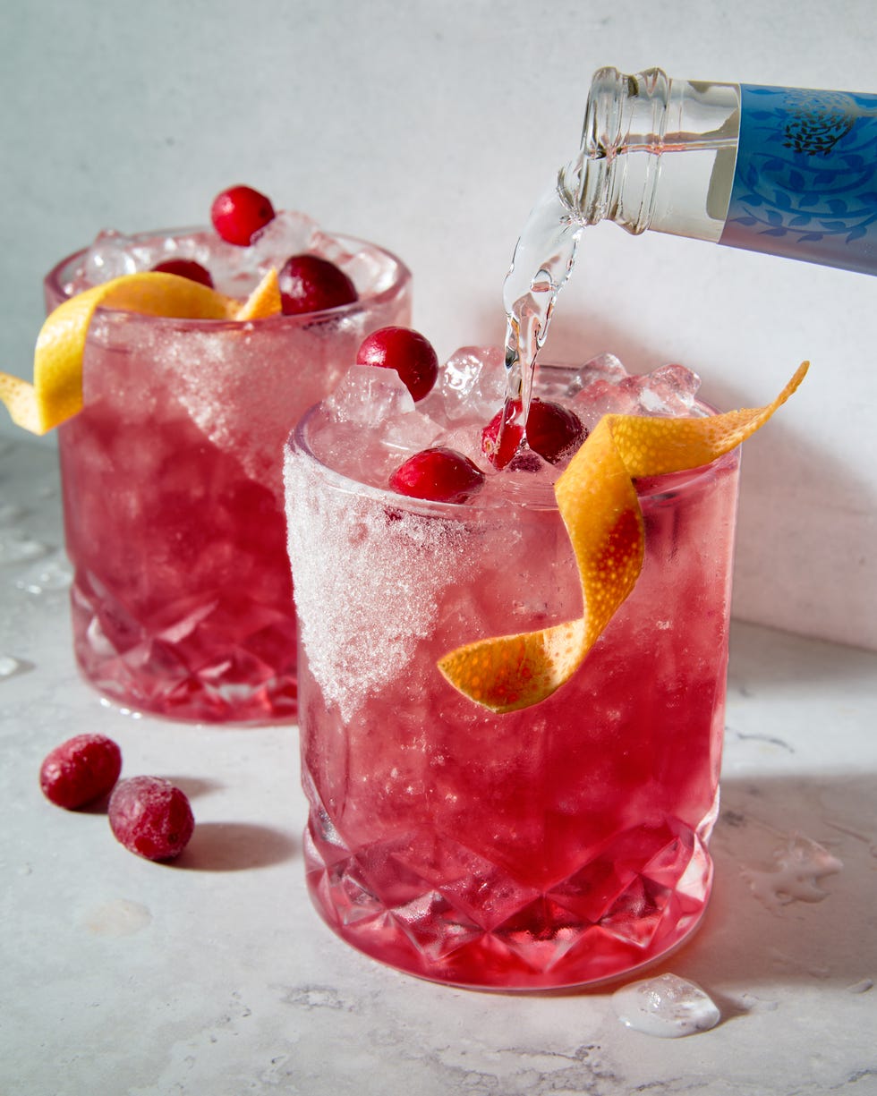 a short glass with a sugar rim, filled with a tequila grapefruit and cranberry cocktail, garnished with a grapefruit twist and fresh cranberries