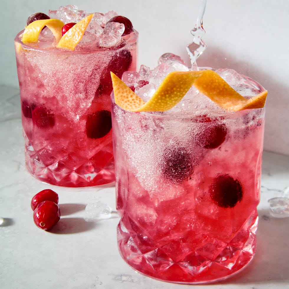 a short glass with a sugar rim, filled with a tequila grapefruit and cranberry cocktail, garnished with a grapefruit twist and fresh cranberries