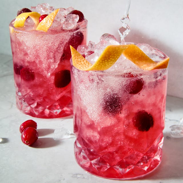 a short glass with a sugar rim, filled with a tequila grapefruit and cranberry cocktail, garnished with a grapefruit twist and fresh cranberries
