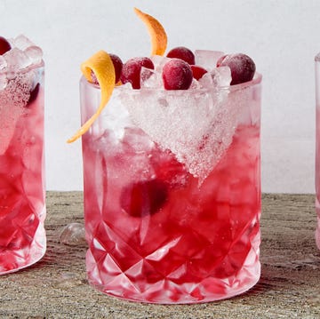 Cranberry Paloma a short glass with a sugar rim, filled with a tequila grapefruit and cranberry cocktail, garnished with a grapefruit twist and fresh cranberries