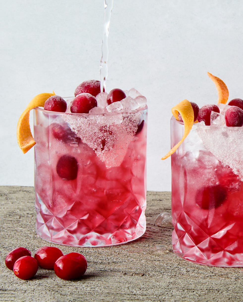a short glass with a sugar rim, filled with a tequila grapefruit and cranberry cocktail, garnished with a grapefruit twist and fresh cranberries