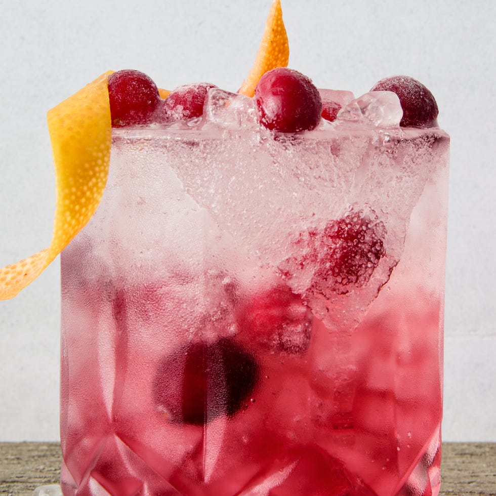 a short glass with a sugar rim, filled with a tequila grapefruit and cranberry cocktail, garnished with a grapefruit twist and fresh cranberries