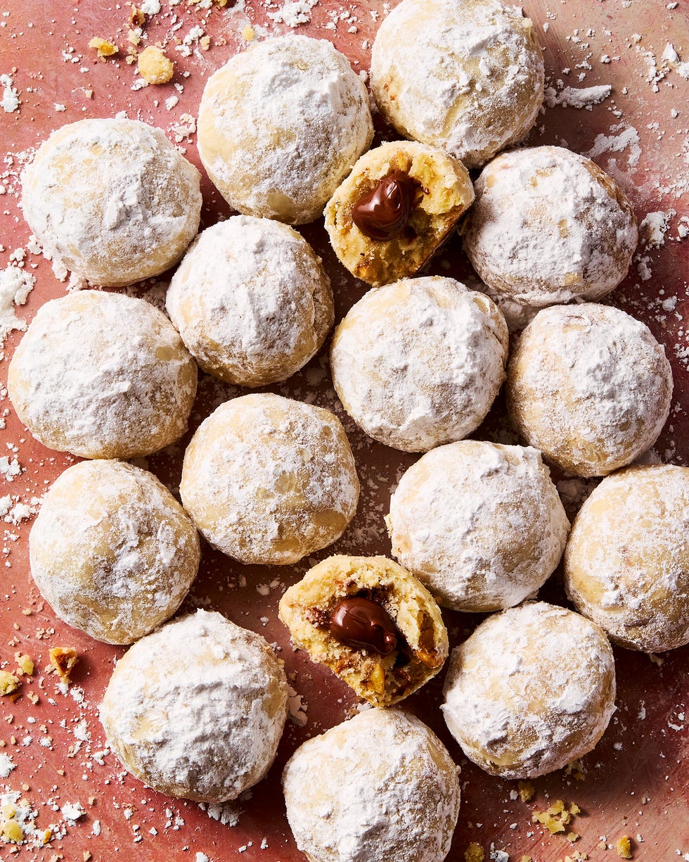 round hazelnut shortbread cookies coated in powdered sugar with nutella in the center of each cookie