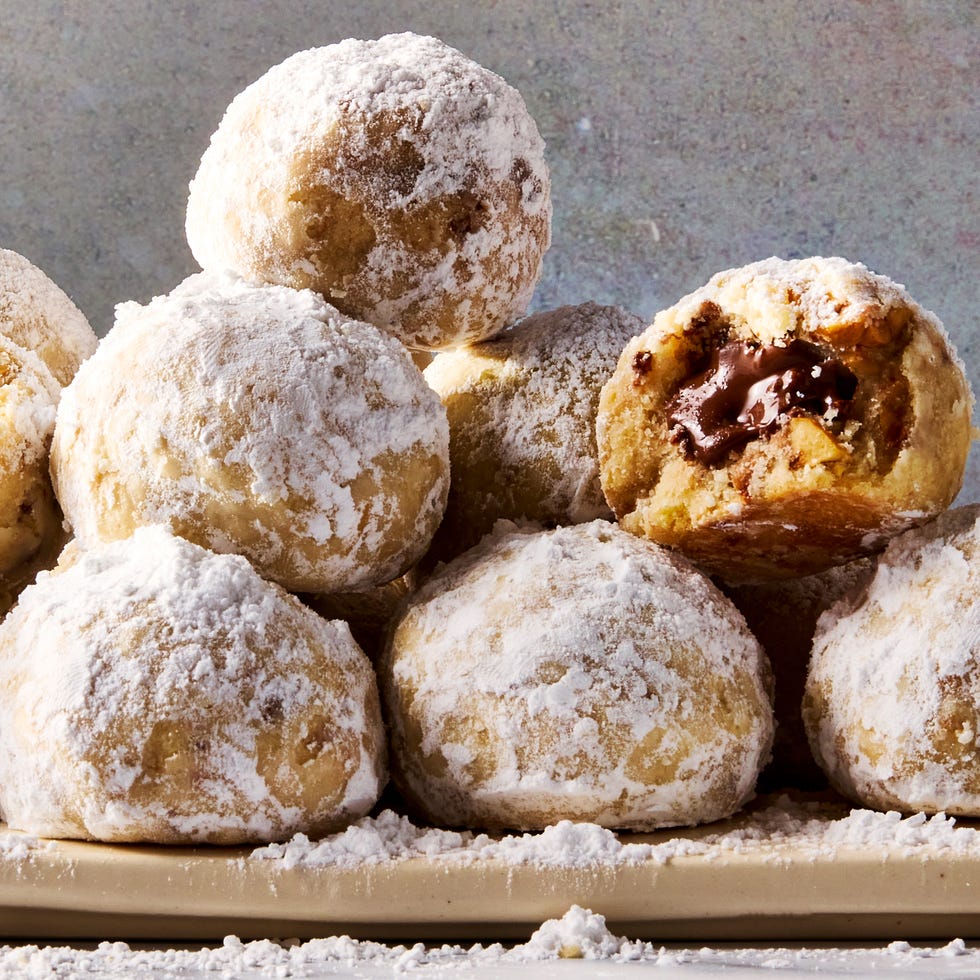 round hazelnut shortbread cookies coated in powdered sugar with nutella in the center of each cookie