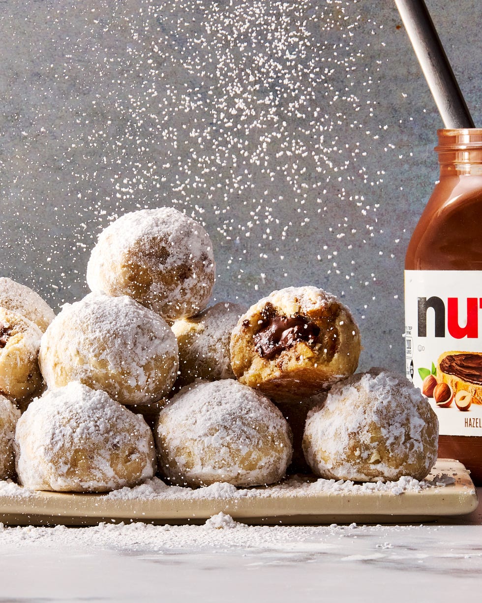 round hazelnut shortbread cookies coated in powdered sugar with nutella in the center of each cookie