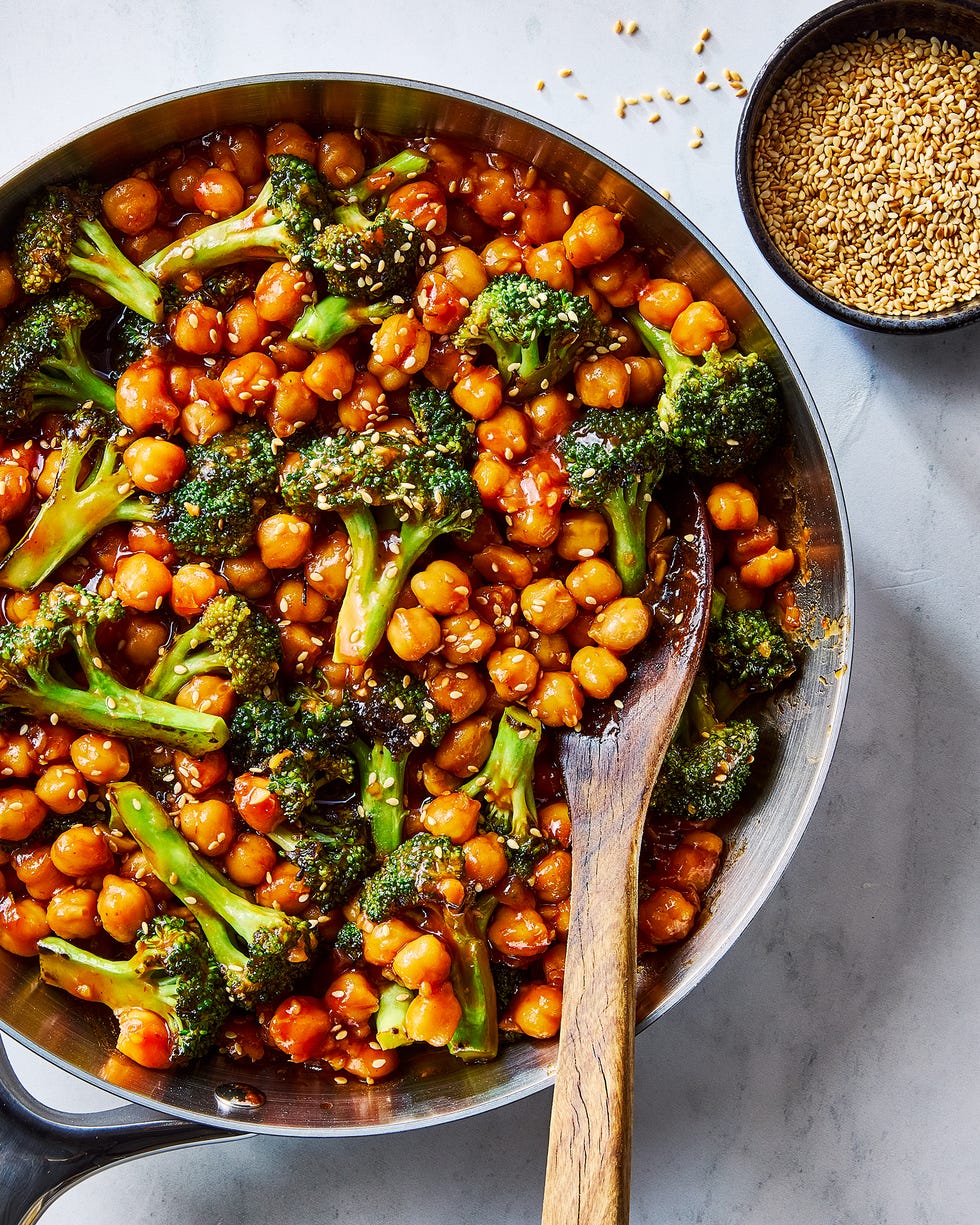 Sticky sesame chickpeas and broccoli added to pan with wooden spoon