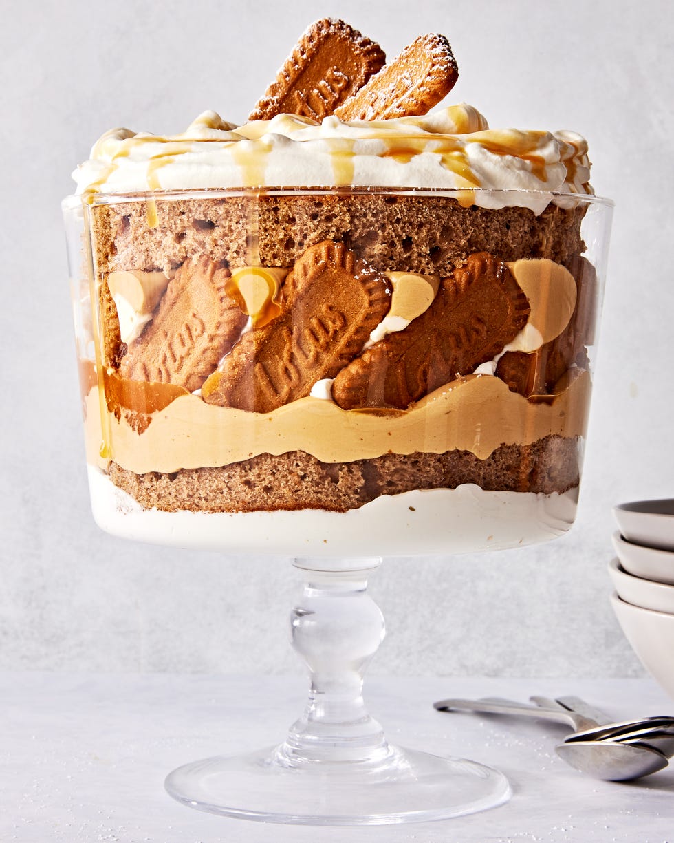 a trifle dish filled with layers of spice cake, caramel, cookie butter mousse, whipped cream, and biscoff cookies