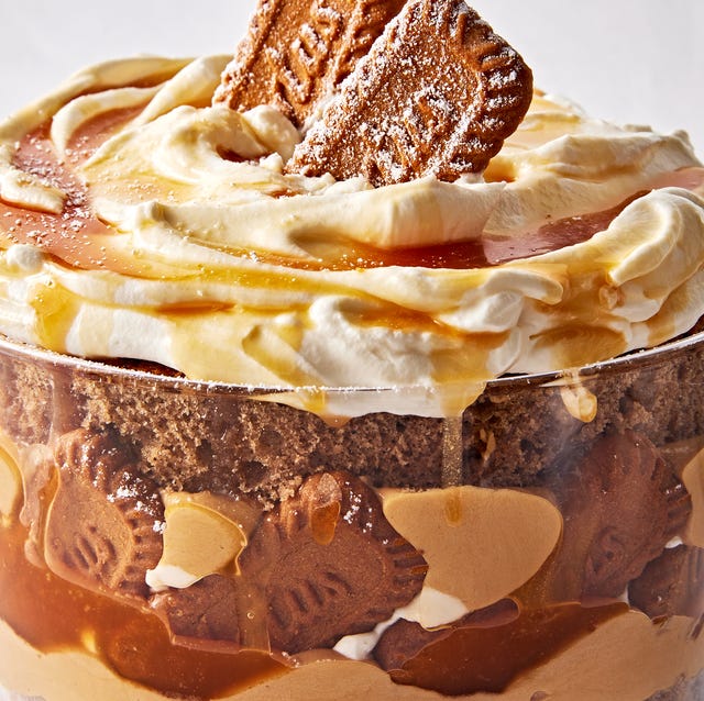 a trifle dish filled with layers of spice cake, caramel, cookie butter mousse, whipped cream, and biscoff cookies