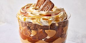 a trifle dish filled with layers of spice cake, caramel, cookie butter mousse, whipped cream, and biscoff cookies