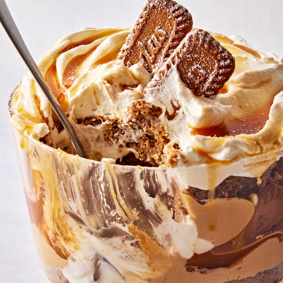 a trifle dish filled with layers of spice cake, caramel, cookie butter mousse, whipped cream, and biscoff cookies