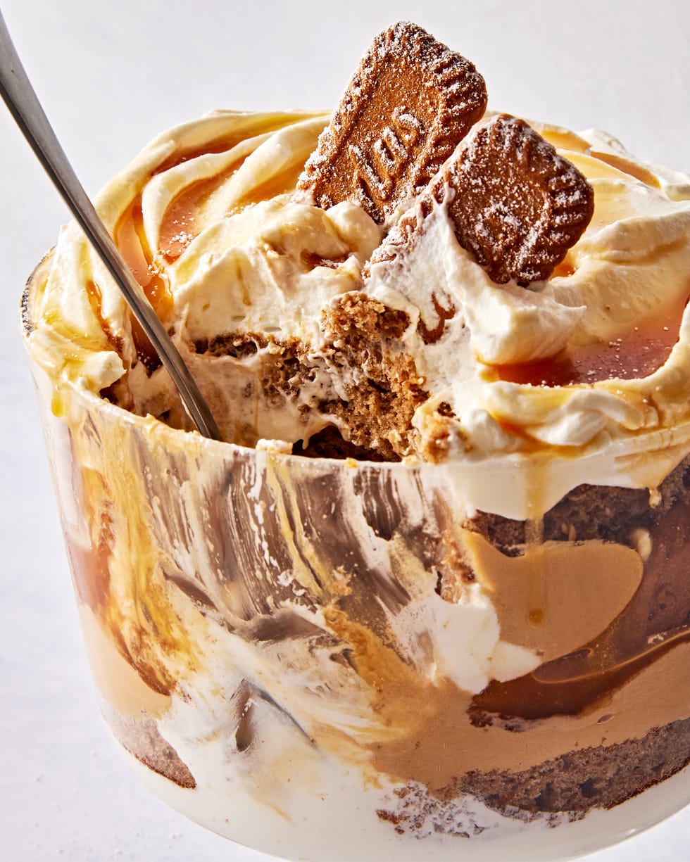 a trifle dish filled with layers of spice cake, caramel, cookie butter mousse, whipped cream, and biscoff cookies
