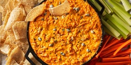buffalo chicken dip in a skillet beside carrots, celery, and tortilla chips