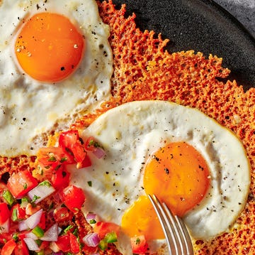 cheesy frico fried egg tostadas on a black plate with pico de gallo