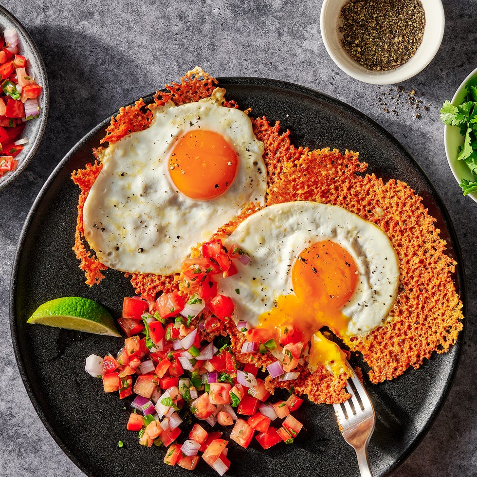 cheesy frico fried egg tostadas on a black plate with pico de gallo