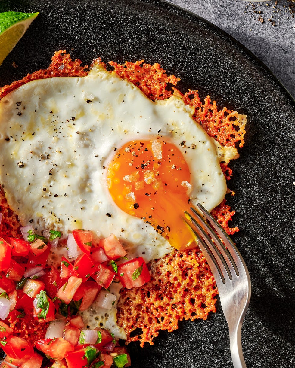 cheesy frico fried egg tostadas with pico de gallo on a black plate