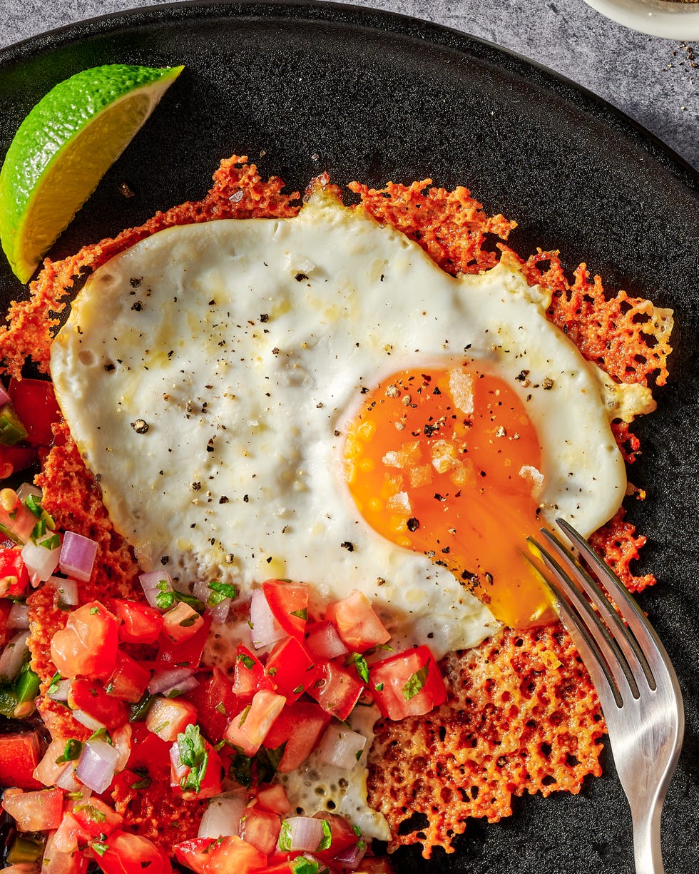 cheesy frico fried egg tostadas on a black plate with pico de gallo