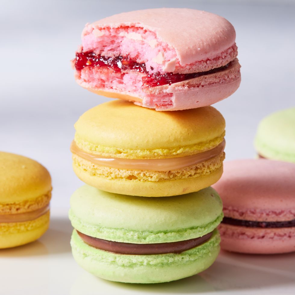 a stack of green, yellow, and pink macarons with a bite taken out of the pink one