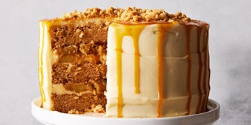 salted caramel apple crumble cake topped with caramel and crumbles on a cake stand