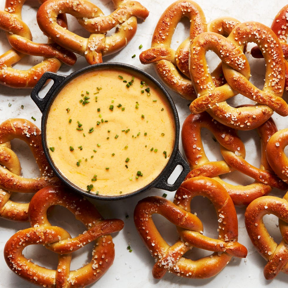 beer cheese in a black pot topped with chives surrounded by soft pretzels