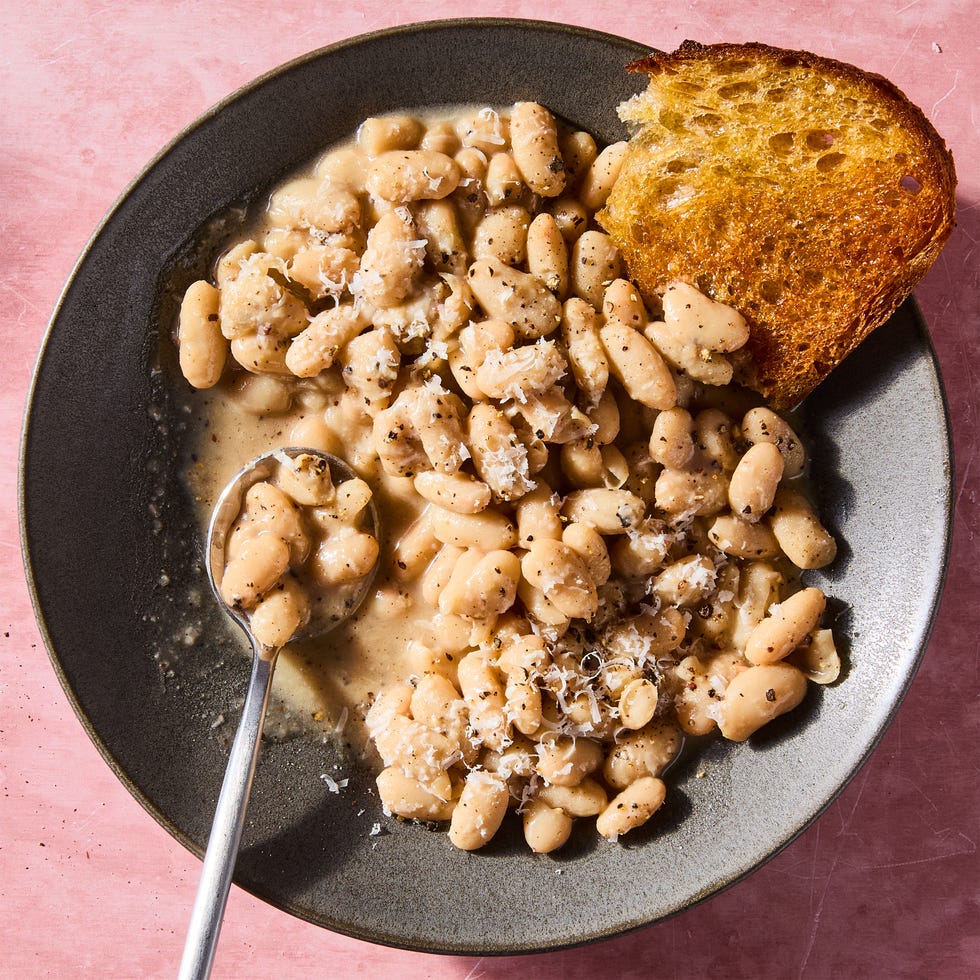 cacio e pepe white beans in a grey bowl with a piece of bread