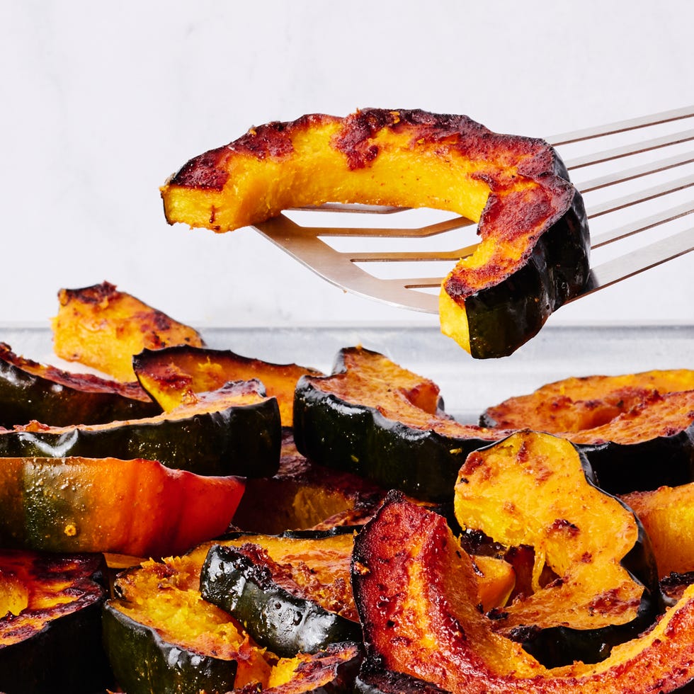 a spatula lifting a piece of acorn squash off the sheet pan