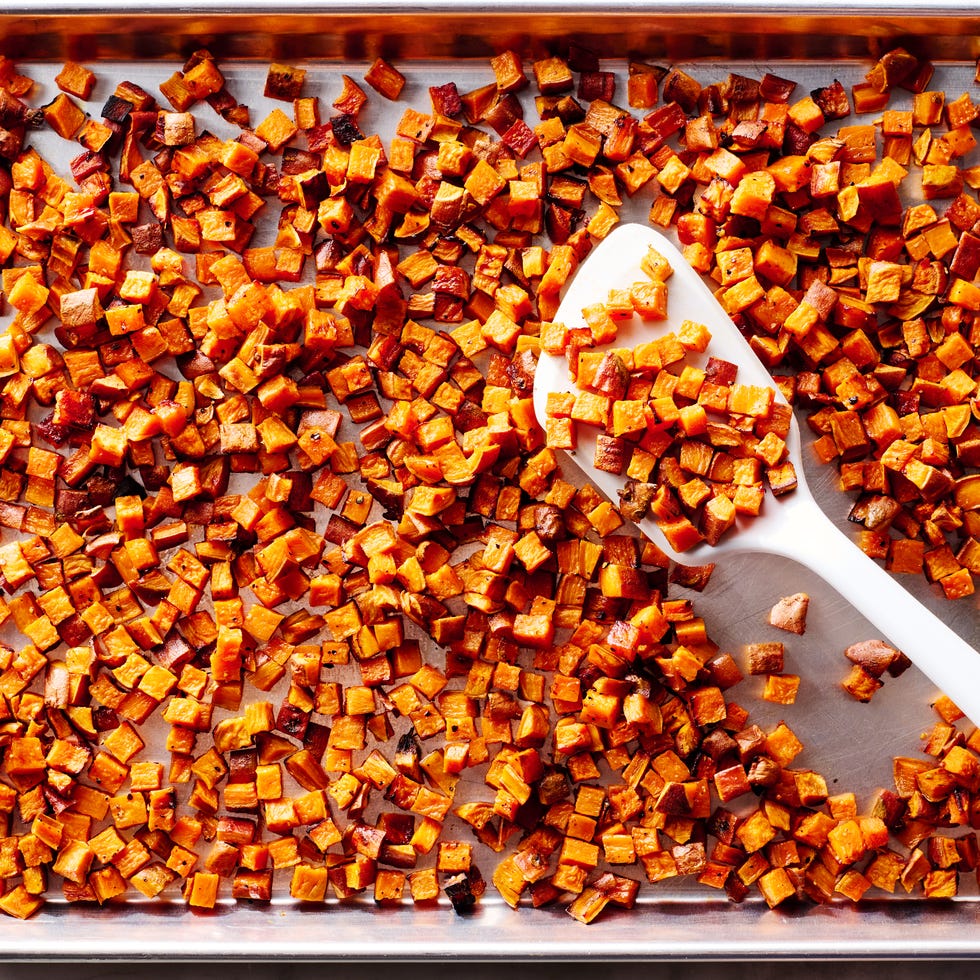 roasted sweet potatoes on a sheet pan with a white spatula
