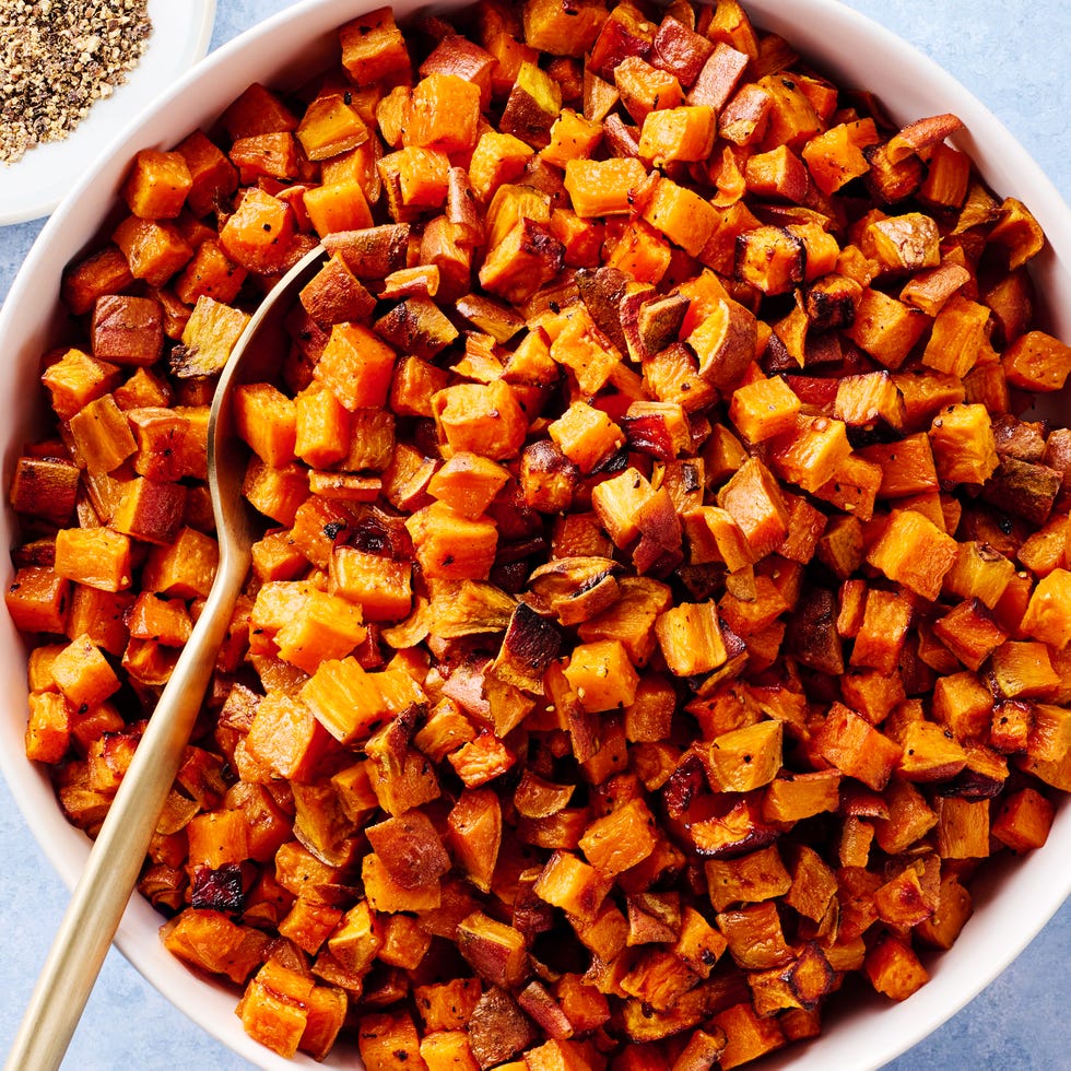 roasted sweet potatoes in a bowl beside a plate of black peppers