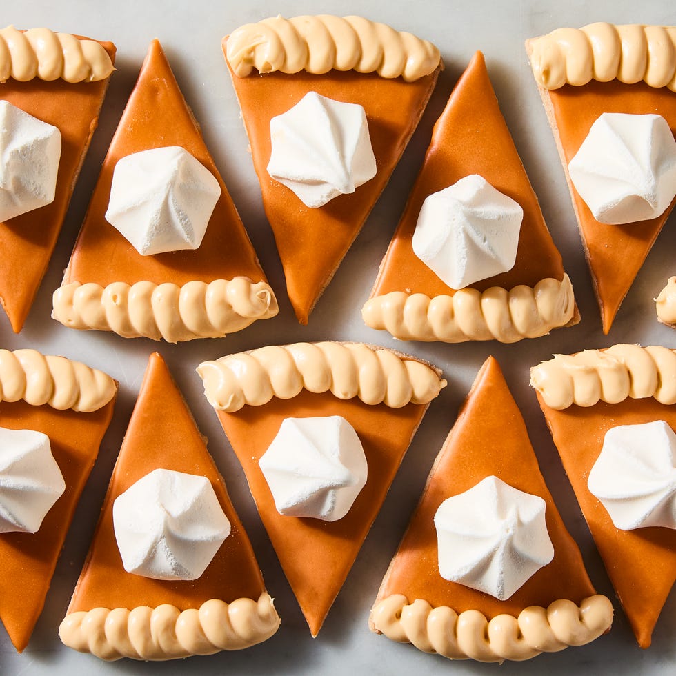 triangular spiced shortbread cookies coated in orange icing, beige frosting, and a vanilla meringue cookie